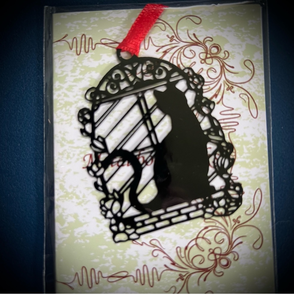 Black cat in garden window metal ornament or bookmark with red ribbon